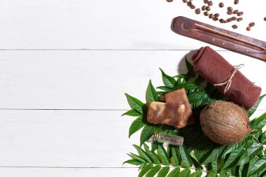 Kahve çekirdekleri, kahverengi havlu, Hindistan cevizi ve Beyaz ahşap zemin üzerine yeşil yaprakları ile doğal el yapımı sabunlar
