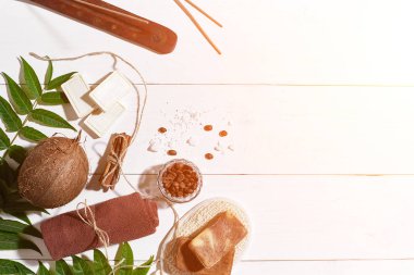 Doğal el yapımı kahve çekirdekleri, tarçın, deniz tuzu, lif kabağı, kahverengi havlu, Hindistan cevizi ve beyaz ahşap zemin üzerine yeşil yaprakları sabunlar. Güneş parlaması