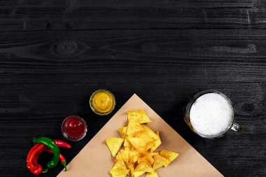 Atıştırma için parti, cips, cips Soslar: domates ketçap, hardal ve bira bir siyah arka plan üzerine bir fincan. Üstten Görünüm, kopya alanı