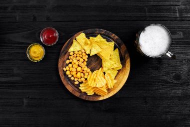 Atıştırma için parti, cips, cips Soslar: domates ketçap, hardal ve bira bir siyah arka plan üzerine bir fincan. Üstten Görünüm, kopya alanı