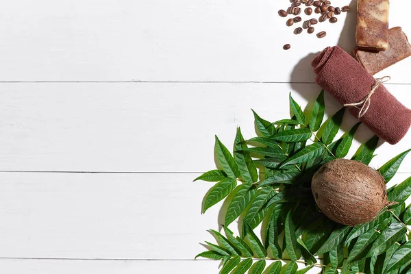 Kahve çekirdekleri, kahverengi havlu, Hindistan cevizi ve Beyaz ahşap zemin üzerine yeşil yaprakları ile doğal el yapımı sabunlar