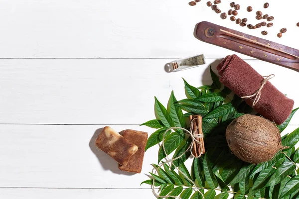 Kahve çekirdekleri, kahverengi havlu, Hindistan cevizi ve Beyaz ahşap zemin üzerine yeşil yaprakları ile doğal el yapımı sabunlar