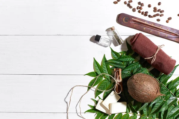 Kahve çekirdekleri, kahverengi havlu, Hindistan cevizi ve Beyaz ahşap zemin üzerine yeşil yaprakları ile doğal el yapımı sabunlar