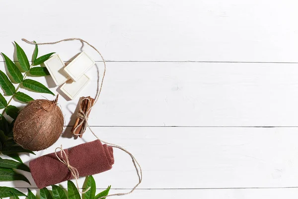 Sabun buatan tangan alami dengan kayu manis, handuk coklat, kelapa dan daun hijau dengan latar belakang kayu putih — Stok Foto