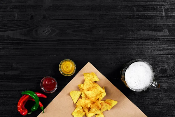 Atıştırma için parti, cips, cips Soslar: domates ketçap, hardal ve bira bir siyah arka plan üzerine bir fincan. Üstten Görünüm, kopya alanı