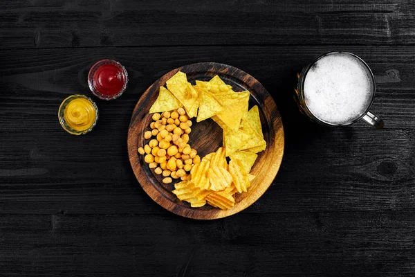 Atıştırma için parti, cips, cips Soslar: domates ketçap, hardal ve bira bir siyah arka plan üzerine bir fincan. Üstten Görünüm, kopya alanı