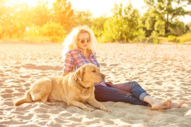 Onun köpeği kumsalda genç kadınla. Güneş parlaması