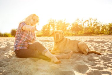 Onun köpeği kumsalda genç kadınla. Güneş parlaması