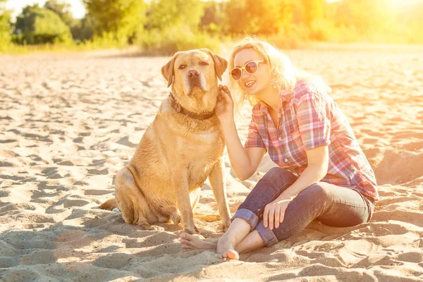 Onun köpeği kumsalda genç kadınla. Güneş parlaması