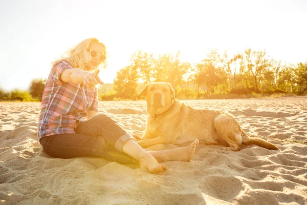 Onun köpeği kumsalda genç kadınla. Güneş parlaması