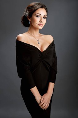 Gri arka planda siyah elbiseli güzel bir kadın.