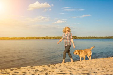 Mutlu genç kadın onun altın geri almak ile bir plaj boyunca gün batımında yürüyüş. Güneş parlaması