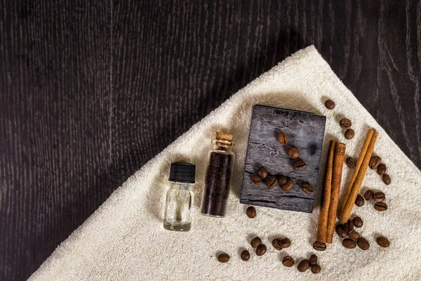 Set Spa in marrone: sapone naturale, olio aromatico, bastoncini di cannella, chicchi di caffè e asciugamano su fondo legno . — Foto Stock