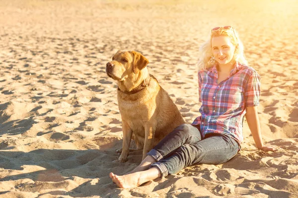 Onun köpeği kumsalda genç kadınla. Güneş parlaması