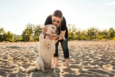 Genç kadın eğitim labrador retriever köpek gün batımında sahilde