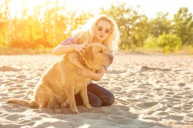 Onun köpeği kumsalda genç kadınla. Güneş parlaması