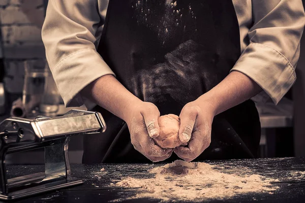 Şef hamur makarna için ahşap bir masaya sağlar.