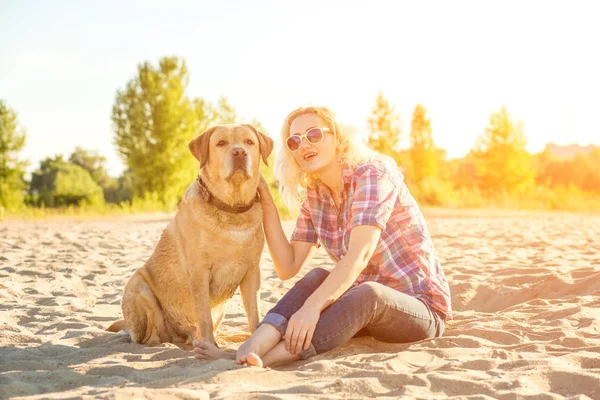 Onun köpeği kumsalda genç kadınla. Güneş parlaması