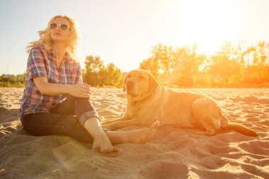 Onun köpeği kumsalda genç kadınla. Güneş parlaması