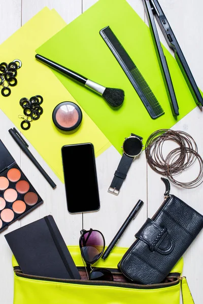 Cosmetica en womens accessoires viel uit de groene handtas op witte achtergrond. — Stockfoto