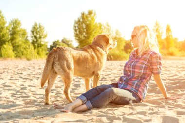 Onun köpeği kumsalda genç kadınla. Güneş parlaması