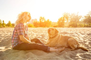 Onun köpeği kumsalda genç kadınla. Güneş parlaması