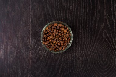 Kahve çekirdekleri bir cam kase - üstten görünüm. Siyah arka plan üzerine.