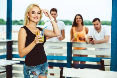 Sarışın kız bir barda bir yaz terasında kokteyl içecekler