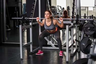 Spor salonundaki simülatörde egzersiz yapan kaslı genç kadın.