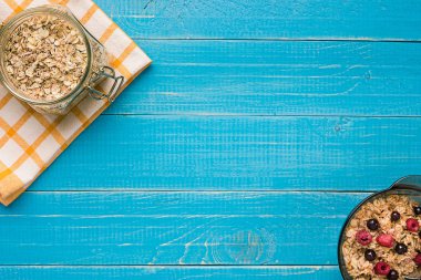 Mavi ahşap arka plan, üstten görünüm kaşık süt ve meyve bir kase ile yulaf gevreği