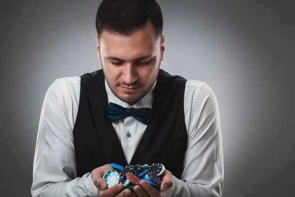 Молодий чоловік у сорочці та жилеті показує свої покерні чіпи, студійний знімок — стокове фото