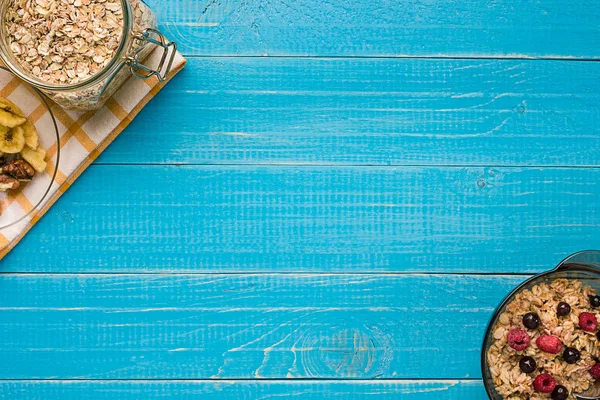 Mavi ahşap arka plan, üstten görünüm kaşık süt ve meyve bir kase ile yulaf gevreği