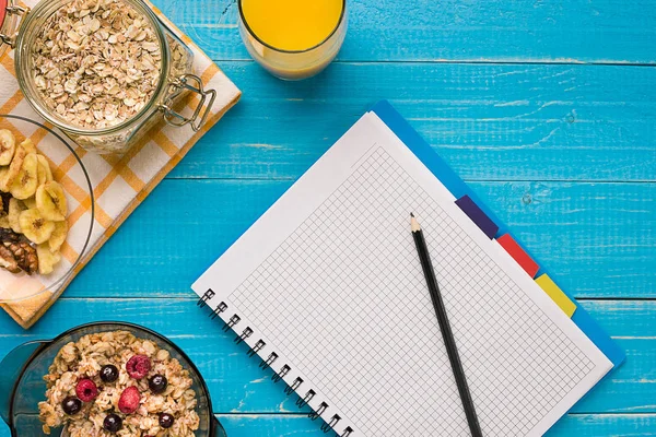 Mavi ahşap arka plan, üstten görünüm kaşık süt ve meyve bir kase ile yulaf gevreği