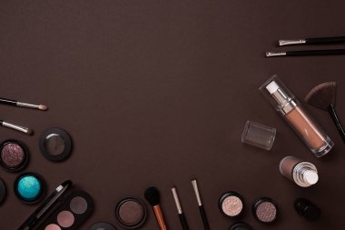 Renkli kozmetik kahverengi çalışma alanı ile kopya alanı üzerinde. Kozmetik yapmak sanatçı nesneleri: ruj, göz gölgeler, toz, makyaj için araçlar. Üstten Görünüm.