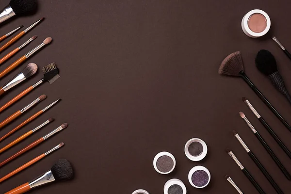 Cepillo para maquillaje, sombra de ojos, vista desde arriba. Sobre un fondo marrón — Foto de Stock