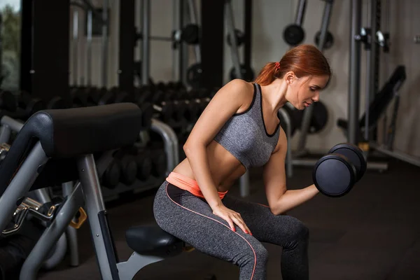 Spor salonunda dumbbells ile egzersizleri yapıyor kadın — Stok fotoğraf