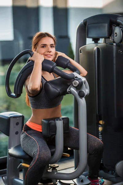 Mięśni młoda kobieta robi ćwiczenia na symulatorze siłowni — Zdjęcie stockowe