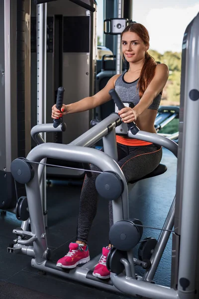 Muskulöse junge Frau macht im Fitnessstudio Übungen auf dem Simulator — Stockfoto