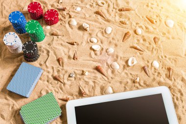 Tatil kavramı - beyaz kum deniz kabuklarını, renkli poker fişleri ve kartları ile kumar. Üstten Görünüm