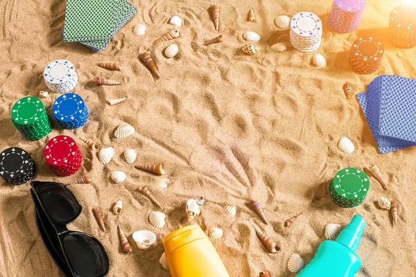 Tatil kavramı - beyaz kum deniz kabuklarını, renkli poker fişleri ve kartları ile kumar. Üstten Görünüm
