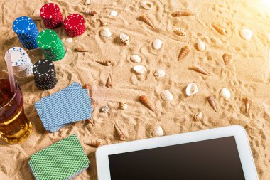 Tatil kavramı - beyaz kum deniz kabuklarını, renkli poker fişleri ve kartları ile kumar. Üstten Görünüm