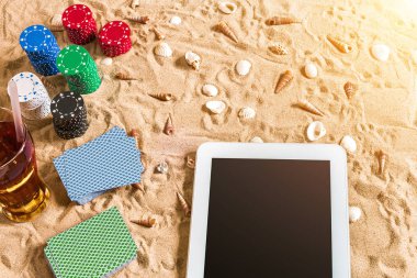 Online poker oyunu ile dijital tablet ve fiş destesi şeklinde sahilde. Üstten Görünüm