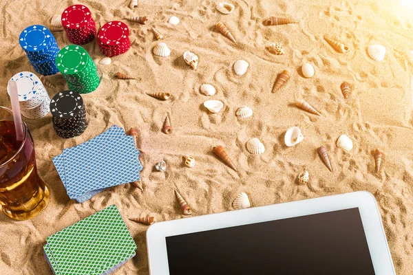 Tatil kavramı - beyaz kum deniz kabuklarını, renkli poker fişleri ve kartları ile kumar. Üstten Görünüm