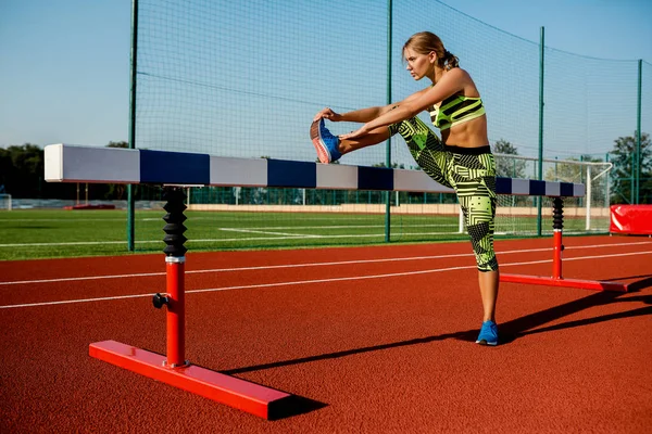 Genç, güzel bir kız atlet spor stadyum ısınma yapıyor