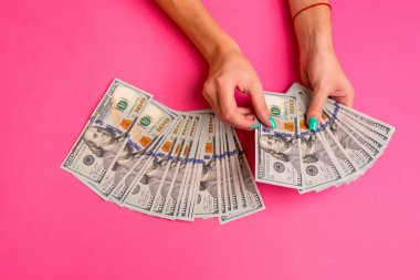 Bir kadın para onun elinde tutuyor. Pembe bir arka plan. Üstten Görünüm kopya alanı.