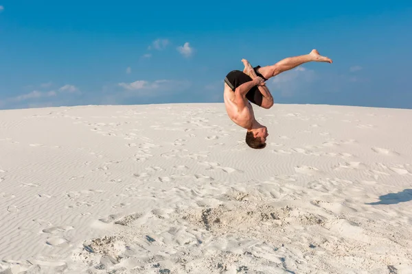 Porträt eines jungen Parkour-Mannes, der Flip oder Salto auf dem Sand macht. — Stockfoto