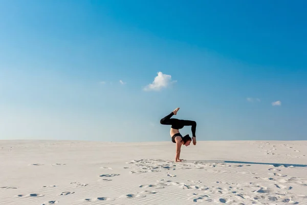 Junge Frau übt Handstand am Strand mit weißem Sand und strahlend blauem Himmel — Stockfoto