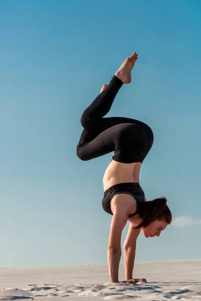 Junge Frau übt Handstand am Strand mit weißem Sand und strahlend blauem Himmel — Stockfoto