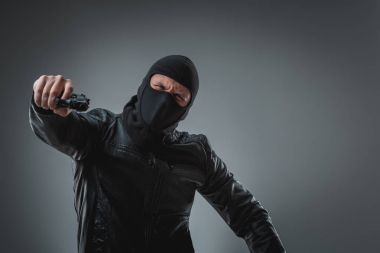 Kameraya bakarak maskeli soyguncu silahla.