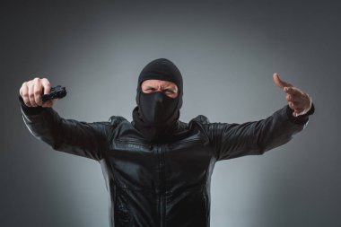 Kameraya bakarak maskeli soyguncu silahla.